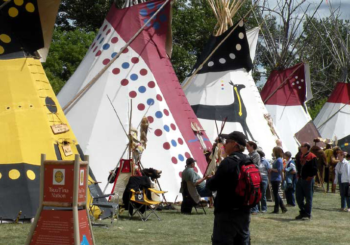 A row of teepees and a croud at the Stampede's Elbow River Camp.